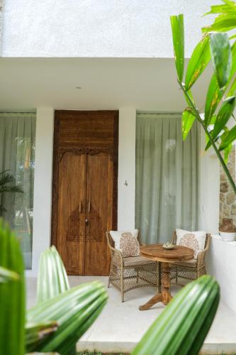 a patio with a table and chairs and a wooden door at The Balangan Hotel in Jimbaran