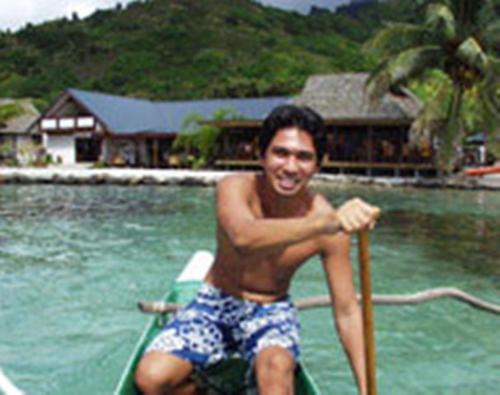 a man sitting on a boat in the water at Pension Motu Iti in Pihaena