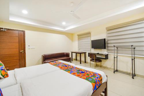 a bedroom with a bed and a desk and a television at FabHotel Prime AM Suites - Nr Yashoda Hospitals in Hyderabad