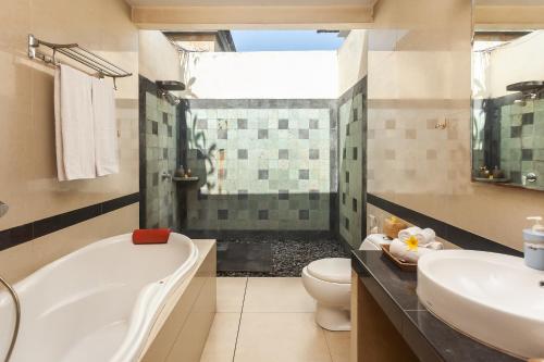 a bathroom with a tub and a toilet and a sink at Kadiga Villas Ubud by GenuineHost in Ubud