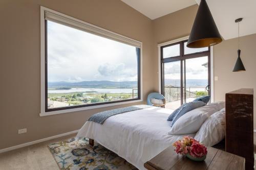 a bedroom with a large window with a bed and a table at River Haven serene spacious with river views in Launceston