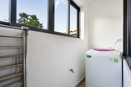 Habitación con ventanas y nevera pequeña. en Tin Tin Apartment, en Ho Chi Minh