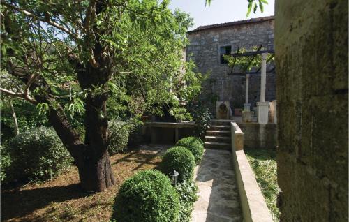 a garden with a tree and a stone building at Three-Bedroom Holiday Home In Blato in Blato