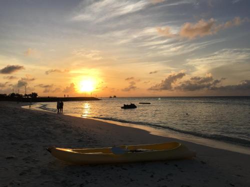 a yellow kayak sitting on the beach with the sunset at Faza View Inn, Maafushi in Maafushi