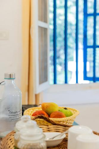 a basket of fruit and a bottle of water on a table at Wildflower Villas - All Villa Hotel, Family Run in Candolim