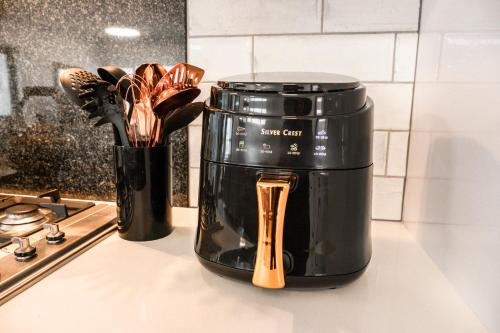 a black coffee pot on a counter with wooden utensils at Hermanus Reefs in Hermanus