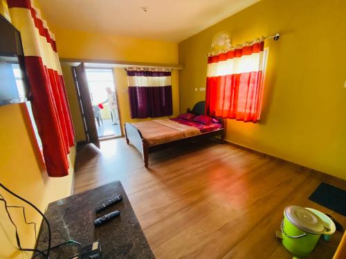 a small room with a bed and red curtains at Vibe n rejoice in Ooty