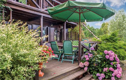 une terrasse en bois avec deux chaises et un parasol dans l'établissement 2 Bedroom Beautiful Home In Nowe Warpno, à Nowe Warpno