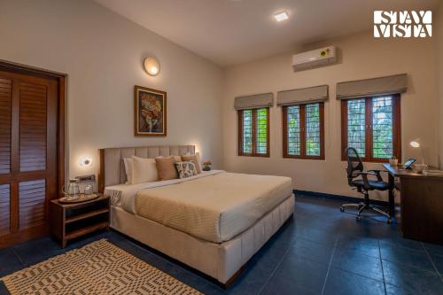 a bedroom with a bed and a desk in it at StayVista at The Lakeshore with Lake View, WiFi, Garden in Bengaluru