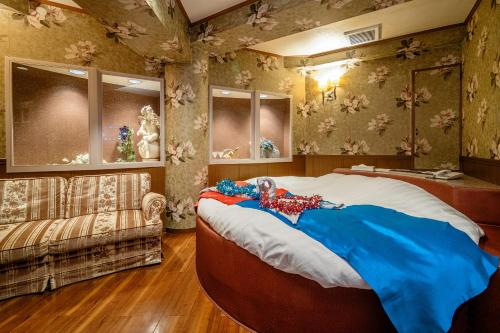 a bedroom with a large bed and a couch at Hotel SUNROAD Adult Only in Tokyo