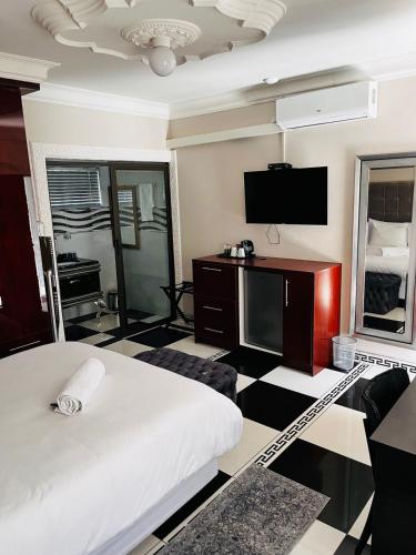 a hotel room with a bed and a flat screen tv at Papiano Boutique Hotel in Bloemfontein