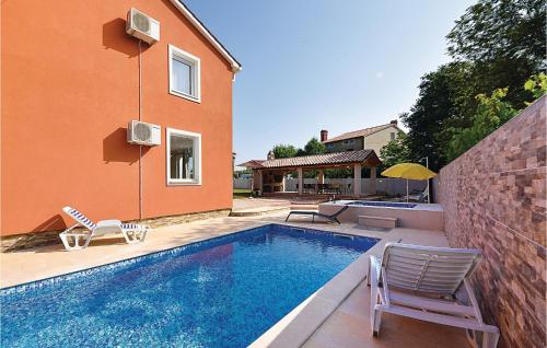 a swimming pool with two chairs and a house at Awesome Home In Valbandon in Štinjan