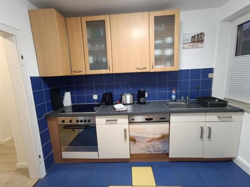 a small kitchen with blue tiles on the wall at FeWo Jadebusen mit Fahrradverleih in Wilhelmshaven