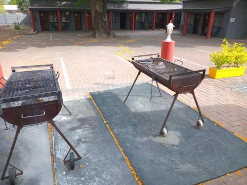 two bbq grill and smoker on a parking lot at Grand Central Guesthouse in Rustenburg
