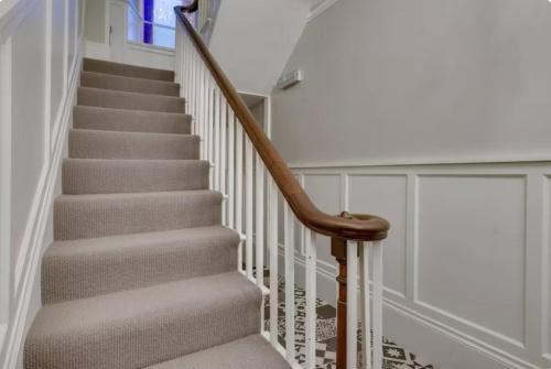 a stairway with a wooden handrail and white stairs at Sedbergh Penthouse - KingBed - Tv - Wifi in Sedbergh
