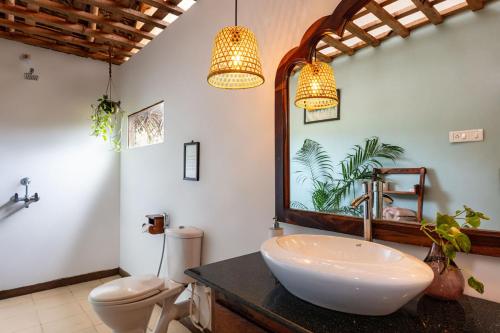 a bathroom with a sink and a toilet and a mirror at Akasa Goa in Palolem