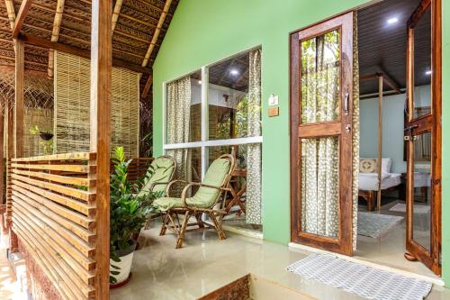 a home with green walls and a porch with chairs at Akasa Goa in Palolem