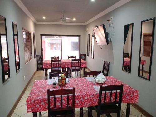 a dining room with tables and chairs with red table cloth at Grand Central Guesthouse in Rustenburg