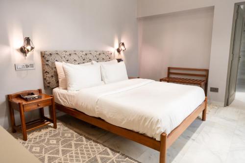 a bedroom with a bed with white sheets and a table at Girisadan Boutique Stay in Jaipur
