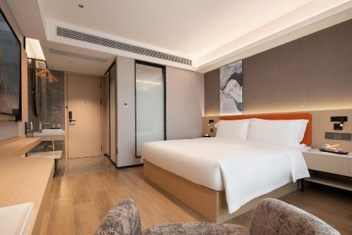 a bedroom with a large white bed and two chairs at Wenchang Meilin Holiday Hotel in Wenchang
