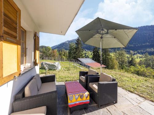 a patio with two chairs and an umbrella at Chalet Verrel near Aletsch Ski Gondolas in Fiesch