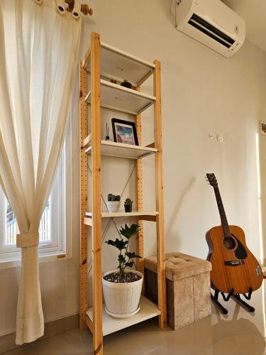 a book shelf with a guitar in a room at Kanaka 2 storey House Nusadua in Badung