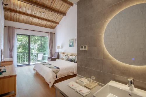 a bedroom with a bed and a bathroom with a sink at Vretreats yunxishang Boutique Hotel in Deqing
