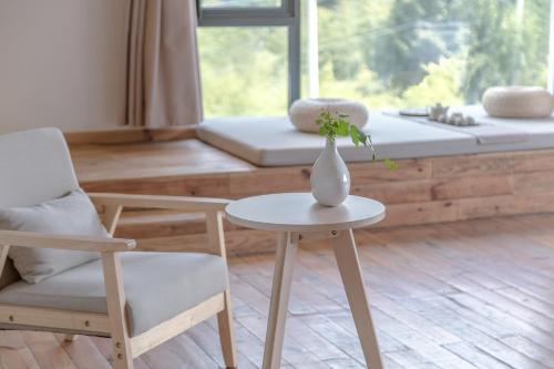 a vase on a table with two chairs and a window at Vretreats yunxishang Boutique Hotel in Deqing
