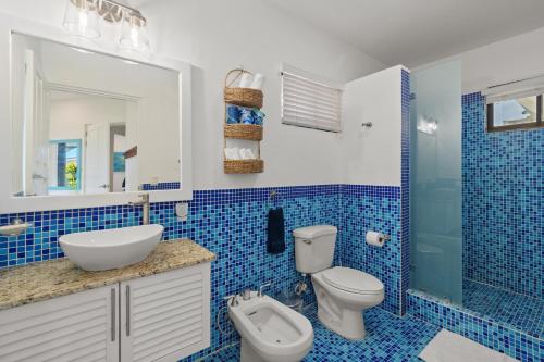 a blue tiled bathroom with a toilet and a sink at Sunshine Escape with a Rooftop Patio in Coco
