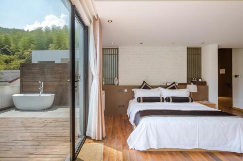 a bedroom with a large bed and a bath tub at Vretreats yunxishang Boutique Hotel in Deqing
