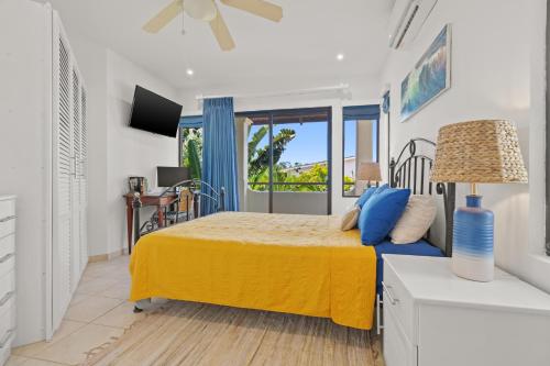 a bedroom with a bed with a yellow bedspread and a window at Sunshine Escape with a Rooftop Patio in Coco