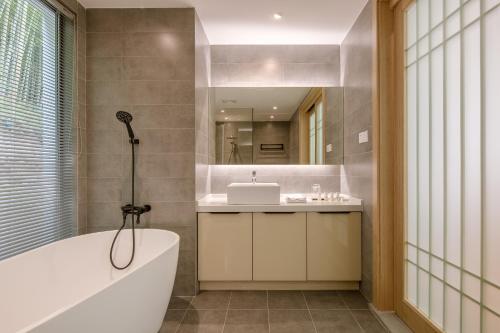 a bathroom with a tub and a sink and a mirror at Vretreats yunxishang Boutique Hotel in Deqing