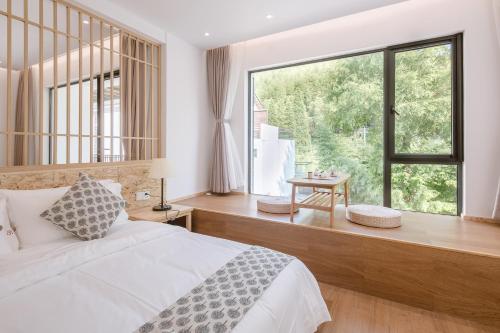 a bedroom with a white bed and a large window at Vretreats yunxishang Boutique Hotel in Deqing