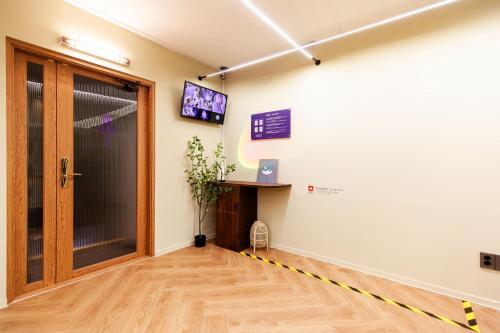 a room with a door and a tv on a wall at Hostel Mihojae Incheon in Incheon