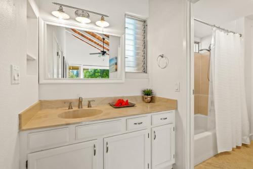a white bathroom with a sink and a mirror at Beautiful Airy 1 Br Condo with Loft Golf Course View Pool Hot tub 209A in Princeville