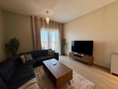 a living room with a couch and a flat screen tv at Canal & Marina View 1br High Floor Pool & Gym in Abu Dhabi