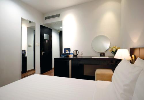 a bedroom with a bed and a desk with a mirror at Palace Hotel Saigon in Ho Chi Minh City