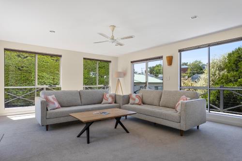 a living room with two couches and a table at Tokenburg Townhouse in Launceston