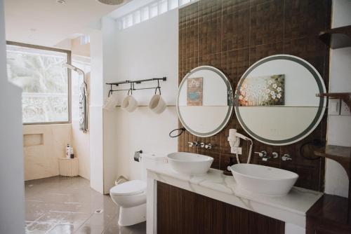 a bathroom with two sinks and two mirrors at The French Villa-Santander Cebu in Santander