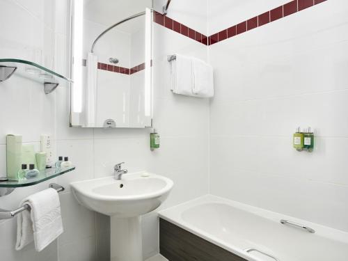 a white bathroom with a sink and a bath tub at Leonardo Hotel Liverpool in Liverpool