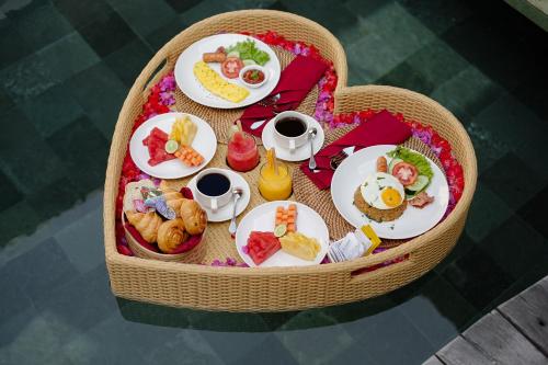 a table with plates of food in a basket at Monique Ubud Villa in Ubud