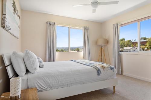 a white bedroom with a bed and windows at Tokenburg Townhouse in Launceston