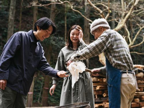 two men and a woman standing around a grill at RITA Izumo Sagiura in Izumo