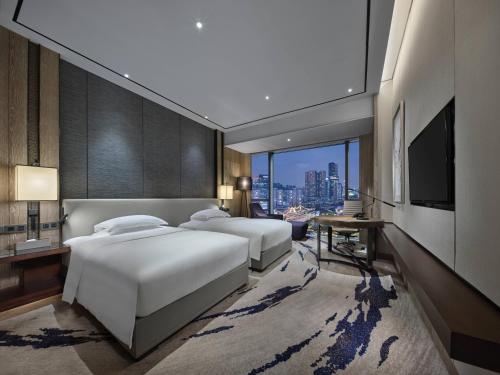 two beds in a hotel room with a television at Hilton Shenzhen Shekou Nanhai in Shenzhen