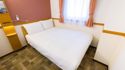 a small bed in a room with a window at Toyoko Inn Takasaki eki Nishi guchi No 2 in Takasaki