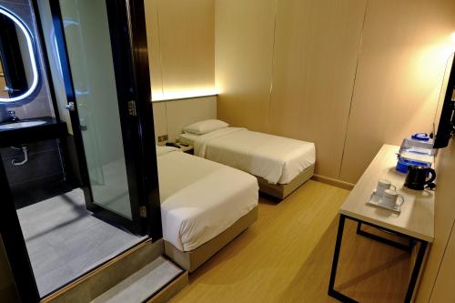 a small room with two beds and a mirror at Ming Paragon Hotel in Kuala Terengganu