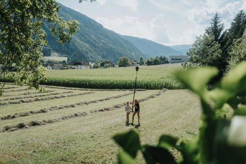 a couple standing in the middle of a field at Residence Obermoarhof - Family Apartments with Pool & Playground in Vandoies