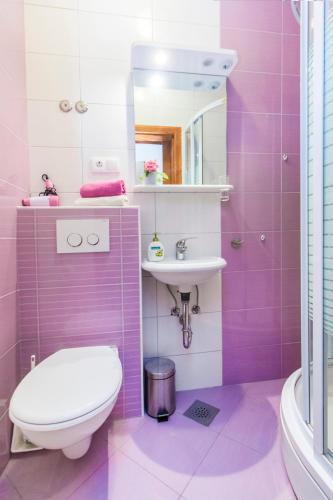 a pink bathroom with a toilet and a sink at Apartments Srdarev Pencov in Vodice
