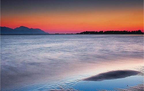 a sunset over the water with a rock in the sand at Two-Bedroom Apartment In Ploce in Ploče