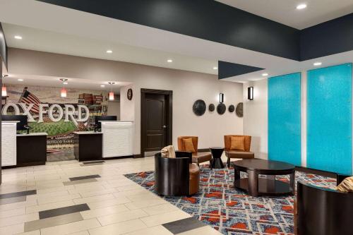a lobby with a waiting area with chairs and tables at La Quinta by Wyndham Oxford - Anniston in Oxford